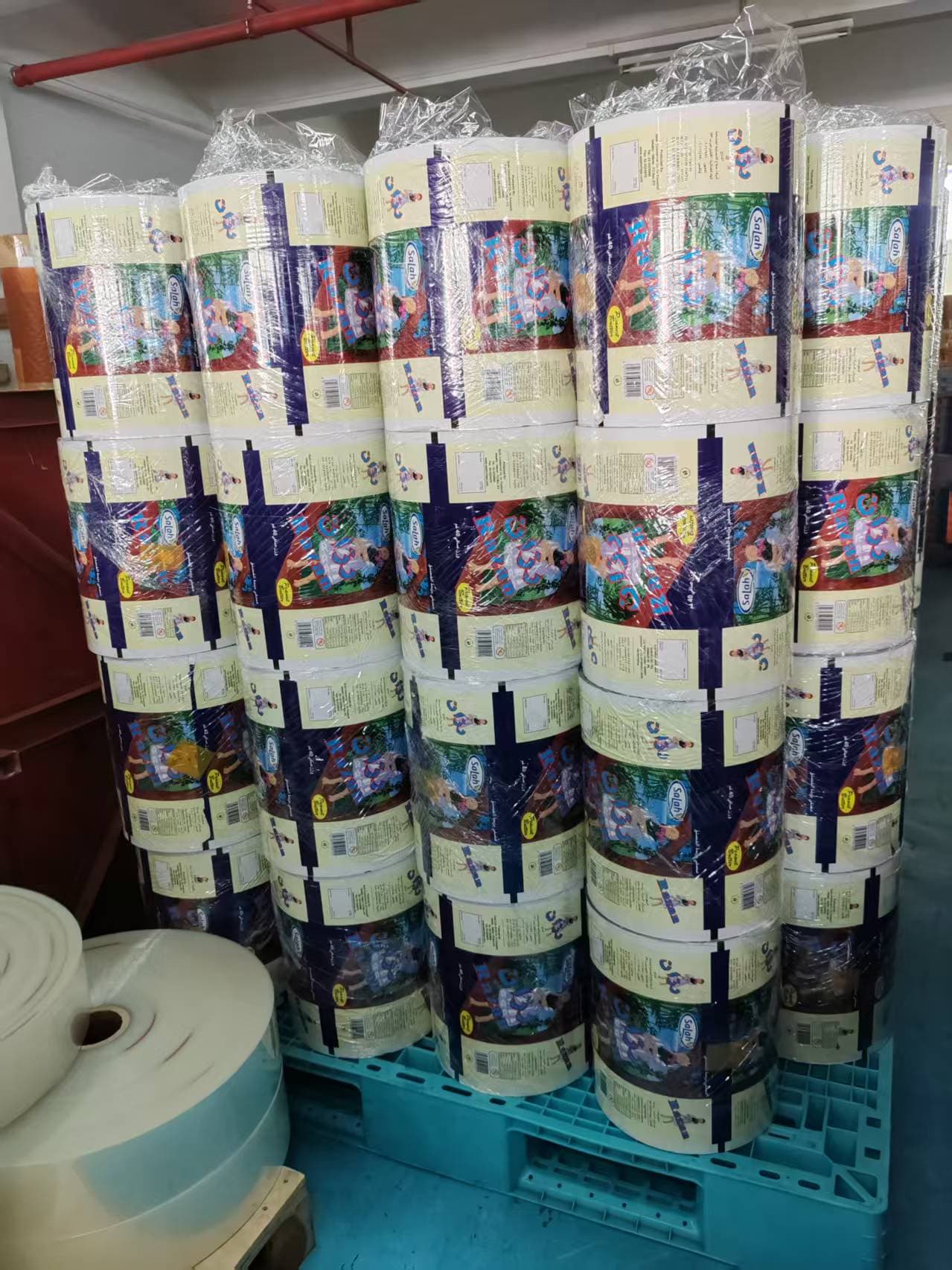 Printed rolls wrapped in stretch film and stacked on a pallet.