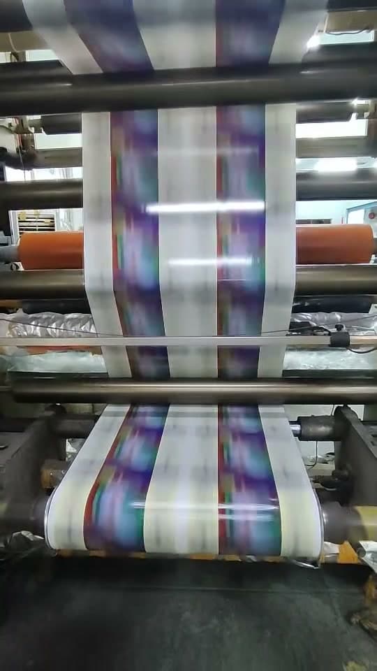 Printed film running through the rollers of a printing press.