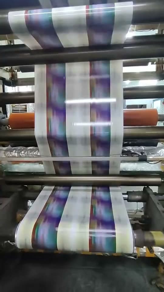 A printing press running, with printed film travelling through the rollers.